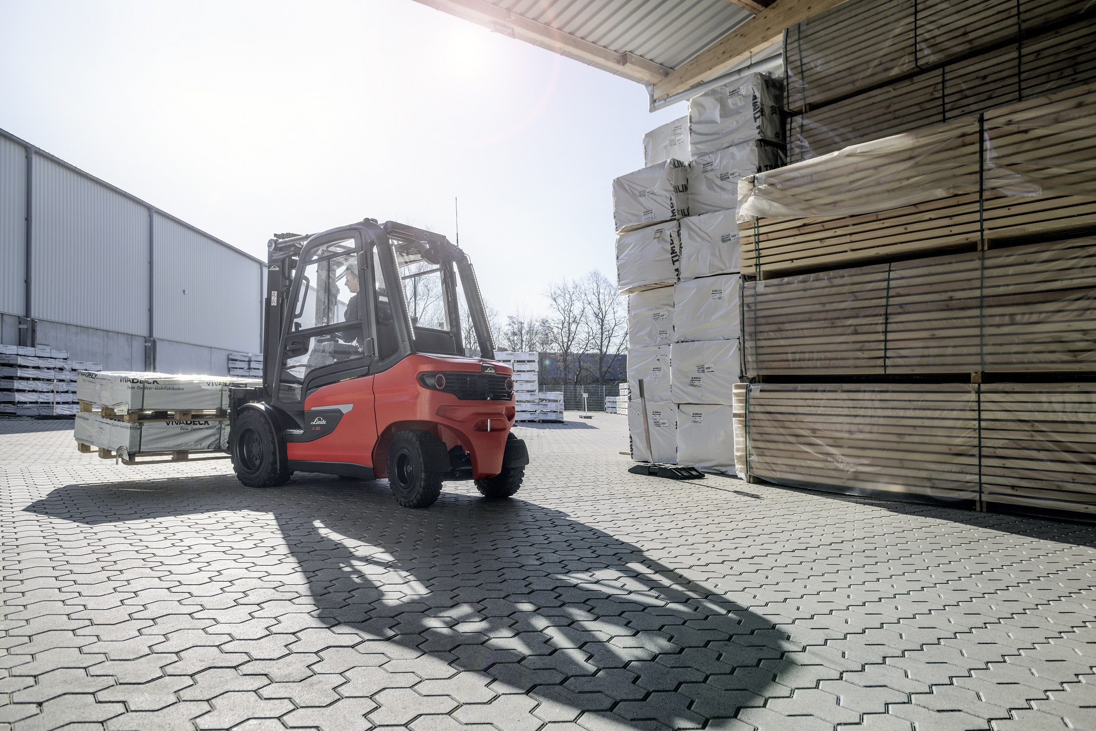 X35 in houtverwerkingsbedrijf rijdt met planken van buiten naar binnen